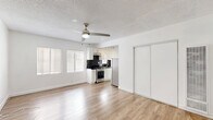 Located at 818 S Mariposa Ave in the Koreatown neighborhood of Los Angeles, this single-floor studio unit offers a practical and well-appointed layout comprising a living area, closet, and full bathroom. The open-concept living and kitchen area is finished with light hardwood-style flooring that extends throughout the space, creating a cohesive and clean aesthetic. Crisp white walls and a textured ceiling contribute to a bright, airy feel, while ceiling fans provide year-round comfort. Natural light enters through windows fitted with blinds, illuminating the space effectively. The kitchen is positioned at the rear of the main room and features white cabinetry, a bold black subway tile backsplash, stainless steel appliances including a gas range and refrigerator, and track lighting overhead. A set of sliding closet doors provides convenient built-in storage within the main living area. The bathroom is clean and functional, finished in white with a vanity, mirror with overhead lighting, and a window that allows natural light. The overall design is minimal and move-in ready, making efficient use of every area within the unit.