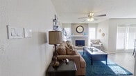 This single-story, 1-bedroom, 1-bathroom home offers a thoughtfully designed layout that maximizes every square foot of its compact footprint. The living room serves as the heart of the home, showcasing a tile-surround fireplace framed by a shiplap accent wall, ceiling fan with light fixture, and textured ceilings. Natural light filters in through multiple windows dressed with white plantation shutters, creating a bright and welcoming atmosphere. Hardwood-style flooring runs through the main living areas, adding warmth and continuity. Adjacent to the living room, the dining area features a mirrored wall that amplifies the sense of space, along with French doors that bring in additional natural light. The bedroom is carpeted for comfort and includes a ceiling fan, a generous walk-in closet with built-in shelving, and a window for natural light. The bathroom is well-equipped with warm wood cabinetry, a granite-style countertop, a large vanity mirror, and a shower-tub combination. The entrance provides a functional transition into the home. Overall, the space presents a cohesive, neutral color palette with tasteful details that balance comfort and practicality throughout.