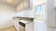 Located at 1221 N Orange Dr in the heart of Los Angeles, this one-bedroom, one-bathroom unit offers a well-organized layout across a single floor. The open-concept kitchen is equipped with white cabinetry, a stainless steel sink, a dishwasher, a stove, a microwave, and a refrigerator. A peninsula counter with a gray stone-style surface connects the kitchen to the dining and living areas, creating a functional and cohesive common space. Light wood plank flooring runs throughout the main living areas, lending a clean, modern aesthetic. The living room is highlighted by a charming fireplace with a white surround and large floor-to-ceiling windows that flood the space with natural light and offer open views of the surrounding Los Angeles skyline. The bedroom is a comfortable size, finished with plush carpeting and a wide window that brings in additional natural light and city views. A dedicated closet provides convenient storage. The bathroom features a combined shower and tub with sliding frosted glass doors, a toilet, and light wood-style flooring. Skylights in the kitchen provide additional ambient illumination. The overall design is bright and neutral, with white walls throughout creating a clean, inviting atmosphere.