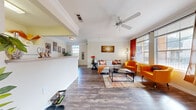 This single-floor residence offers a thoughtfully designed layout that balances comfort and functionality throughout. A welcoming entryway with rich hardwood-style flooring and crown molding leads into the main living area, where large windows dressed in warm drape panels flood the space with natural light. The living room is generously sized, featuring a ceiling fan, crown molding, and ample room for seating arrangements centered around a sleek coffee table. Adjacent to the living area, a cozy dining nook provides an intimate setting for meals, positioned beside a bright window that enhances the airy atmosphere. The galley-style kitchen is well-equipped with white cabinetry, light stone countertops, and white appliances including a range and refrigerator, offering efficient use of space. The bedroom is comfortably sized and benefits from natural light, dual closets for plentiful storage, and a ceiling fan. The full bathroom includes a single-sink vanity with stone countertops, white cabinetry, and a tub-shower combination with tile surround. A dedicated laundry room with shelving adds everyday convenience. Consistent hardwood-style flooring and a neutral color palette tie the entire home together with a clean, cohesive aesthetic.