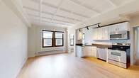 Located in Chicago's storied Gold Coast neighborhood, this 1-bedroom, 1-bathroom unit at 1211 North La Salle Drive blends classic architectural character with modern updates. Distinctive coffered ceilings grace the open-plan living, dining, and kitchen area, creating a sense of depth and elegance throughout. Light hardwood flooring flows continuously across the space, enhancing the bright, airy ambiance delivered by large windows that frame city views. The kitchen is thoughtfully appointed with white shaker cabinetry, dark countertops, a mosaic tile backsplash, stainless steel appliances — including a dishwasher, range, microwave, and refrigerator — and a peninsula that naturally defines the cooking space from the living area. Arched architectural details add a timeless touch between rooms. The spacious bedroom features the same signature coffered ceiling, a closet, and a window with city views. The bathroom offers a clean, modern finish with a tiled shower-tub combination and a wood-accented vanity. A dedicated laundry area with a stacked Samsung washer and dryer adds everyday convenience. Multiple closets throughout provide ample storage. The layout is efficiently organized with hallways connecting all rooms for a cohesive, functional flow.