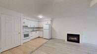 Located at 1199 Lansdowne Ave in Toronto's vibrant Davenport neighbourhood, this well-designed 2-bedroom, 2-bathroom unit offers a clean, modern aesthetic throughout its efficiently planned single-floor layout. Light-toned hardwood flooring runs through most of the space, complemented by crisp white walls and bright white trim, creating a fresh and airy atmosphere.

The living room is a standout feature, anchored by a sleek gas fireplace and a large multi-pane window that frames lush greenery, flooding the room with natural light. The kitchen is functionally appointed with white cabinetry, a classic subway tile backsplash, tile flooring, and full-sized appliances including a refrigerator and electric range. The entry area transitions seamlessly between tile and hardwood, providing a practical landing zone.

Both bedrooms are bright and well-proportioned, each featuring windows with outdoor views. The primary bedroom includes a built-in double closet for ample storage. The two bathrooms are finished with grey stone-look tile flooring — one featuring a tub-shower combination with full subway tile surround, and the other a standalone shower with marble-style tile detailing. Together, these spaces deliver a functional, clean, and comfortable living environment in a well-connected Toronto location.