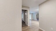 This single-story home offers a thoughtfully designed layout across three bedrooms and two full bathrooms. The interior is finished with a clean, neutral color palette of soft grays and whites, creating a bright and cohesive aesthetic throughout. Light hardwood-style flooring runs through the main living areas, complemented by plush carpeting in the bedrooms for added comfort.

The open living area is bathed in natural light from large windows and features a private exterior door, adding to the airy, welcoming atmosphere. The kitchen is a standout space, outfitted with crisp white shaker-style cabinetry extending to the ceiling for ample storage, a white quartz countertop with a breakfast bar overhang, a white subway tile backsplash, and a full suite of stainless steel appliances including a refrigerator, range, and built-in microwave.

The bedrooms are comfortably sized, with the primary bedroom offering generous closet space. One bedroom features a mirrored sliding-door closet and a ceiling fan, while another provides a quieter, more compact retreat. The bathrooms are finished with white cabinetry, brushed nickel fixtures, and clean tilework. A central hallway connects the bedrooms and bathrooms, ensuring a practical and functional flow throughout the home.