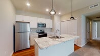 Located at 7325 Liberty Summit Dr in Powell, Ohio, this single-floor residence offers a well-designed open-concept layout that seamlessly connects the kitchen and living areas. The kitchen is a standout feature, showcasing white shaker cabinetry, marble-style countertops, a center island with a built-in sink, and a full suite of stainless steel appliances including a refrigerator, electric range, and over-the-range microwave. Stylish pendant lighting hangs above the island, adding a modern touch. Rich hardwood flooring runs throughout the kitchen and hallway areas, while plush carpet covers the spacious living room and bedrooms. The living room is generously sized, featuring neutral tones, crown molding, and a large window that allows natural light to fill the space. The bedrooms are well-proportioned, with ceiling fans and ample closet storage. The bathrooms are finished with white cabinetry, marble-style countertops, and hardwood flooring. The primary bathroom includes a walk-in glass-door shower, a large vanity mirror, and well-placed lighting. Throughout the home, a consistent neutral color palette and clean finishes create a bright, cohesive, and inviting atmosphere.