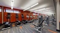 Located at 7912 River Rd in North Bergen, NJ, this fitness center offers a well-organized, single-floor layout designed to support a comprehensive workout experience. The space features bold, energizing décor with deep red accent walls and a coordinated striped carpet in gray, orange, and tan tones that adds visual interest throughout the floor.

The main workout area is lined with a robust selection of cardio equipment, including Star Trac treadmills, elliptical trainers, and stationary bikes with integrated display screens. Along the opposite side, a series of strength and cable machines provides options for targeted resistance training. Full-length mirrors line portions of the walls, enhancing the sense of openness and allowing users to monitor their form.

A secondary zone near the entrance houses free weights, adjustable benches, and stability balls of varying sizes displayed on wall-mounted racks. A water station and waste receptacle are conveniently positioned near the entry doors, alongside a wall clock for easy time management during workouts.

Overhead, linear fluorescent lighting provides bright, even illumination throughout the space. A row of high horizontal windows along the upper wall allows natural light to supplement the interior lighting. The facility is clean, well-maintained, and efficiently arranged to maximize usable floor space for members of all fitness levels.