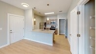 Located at 5067 Elevated View in Chattanooga, Tennessee, this single-floor residence offers a thoughtfully designed layout with modern finishes throughout. The kitchen is a standout feature, showcasing granite countertops, a large center island with a built-in sink, warm-toned cabinetry, stainless steel appliances including a refrigerator, range, microwave, and dishwasher, and elegant pendant lighting. Light hardwood-style flooring runs throughout the main living areas, creating a cohesive and airy feel. The open living area is bright and inviting, highlighted by a ceiling fan and direct access to a private balcony, allowing natural light to fill the space. A dedicated pantry with wire shelving provides ample storage off the kitchen. The bedrooms are carpeted for comfort and offer generous proportions, with one featuring a spacious walk-in closet equipped with wire shelving and hanging racks. The bathrooms are well-appointed with granite-topped vanities, rich wood cabinetry, and full tub-shower combinations. Neutral gray tones and crisp white trim throughout the space lend a clean, contemporary aesthetic. The overall layout is functional and well-organized, making efficient use of space across every room.