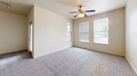 Located at 21 Gramercy Park Dr in Bryan, Texas, this two-story home offers 2 bedrooms and 2 bathrooms across a well-organized layout. The main living level hosts the majority of the living space, while the ground floor provides an attached garage with an automatic opener, offering secure and convenient parking.

The open-concept kitchen and living area serves as the heart of the home. The kitchen is well-appointed with rich dark-brown cabinetry, granite-style countertops, a peninsula with a built-in sink, and a full suite of stainless steel appliances including a range, microwave, and refrigerator. Wood-look flooring and track lighting complete the polished look.

Both bedrooms feature plush carpeting and ceiling fans, with multiple windows allowing for natural light. The primary bedroom is generously sized and includes direct access to a dedicated bathroom and a closet. The second bedroom is comfortable and similarly appointed.

Each of the two bathrooms is finished with dark wood cabinetry, granite-style countertops, wood-look flooring, and a full soaking tub with a tiled surround. A hallway connects the upper-level rooms, with a staircase providing access between floors. Neutral wall tones and clean finishes throughout lend the home a consistent, move-in-ready aesthetic.
