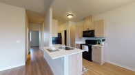 Located at 5069 Countryside St NE in Salem, Oregon, this single-story unit offers a clean, modern aesthetic throughout its thoughtfully designed layout. The open-concept kitchen serves as a central hub, showcasing light wood cabinetry paired with white countertops and a contrasting suite of black appliances, including a refrigerator, range, microwave, and dishwasher. A kitchen island with an integrated sink provides additional workspace and a natural transition into the dining and living areas. Warm-toned luxury vinyl plank flooring flows consistently throughout the main living spaces, enhancing the bright and cohesive feel of the interior.

The living and dining area is well-lit by multiple windows that invite natural light, and a glass door provides direct access to an outdoor balcony, extending the usable living space. A modern multi-bulb pendant chandelier adds a stylish focal point to the dining area. The bedrooms are generously proportioned, featuring the same warm flooring and neutral walls, offering a versatile blank canvas. The bathroom is finished with decorative patterned tile flooring, a full tub-shower combination, and clean white fixtures, adding a distinct design detail to the space.