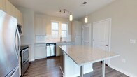 Located at 2170 Snyder Circle in the desirable community of Mount Pleasant, South Carolina, this single-floor home offers a thoughtfully designed layout with clean, contemporary finishes. The kitchen serves as a central highlight of the home, showcasing a large center island topped with speckled granite countertops that provide generous prep and gathering space. White shaker-style cabinetry lines the walls, complemented by a classic subway tile backsplash that adds texture and brightness to the space. Stainless steel appliances, including a dishwasher, are seamlessly integrated into the design. Pendant lighting hangs above the island, while a track light fixture overhead ensures the kitchen is well-lit throughout the day. A window above the sink allows natural light to filter in, enhancing the airy, open feel of the room. Rich dark hardwood flooring runs throughout, grounding the bright white cabinetry and countertops with a warm contrast. Louvered closet doors provide practical storage solutions while maintaining the home's cohesive aesthetic. The overall ambiance is bright, clean, and welcoming, reflecting a modern sensibility well-suited to the Mount Pleasant lifestyle.