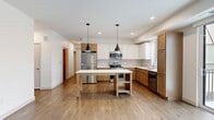 Located at 7570 32nd St N in Oakdale, Minnesota, this thoughtfully designed 4-bedroom, 2-bathroom home offers a clean, modern aesthetic throughout its single-floor layout. The open-concept kitchen serves as the heart of the home, showcasing a striking two-tone cabinetry design with warm wood lower cabinets and crisp white upper cabinets. Stainless steel appliances, a white tile backsplash, white quartz countertops, and a freestanding island with pendant lighting above complete the space with both style and function. Warm hardwood-style flooring flows through the main living areas, lending a cohesive and inviting feel. A hallway with doors on either side provides convenient access to multiple rooms. The spacious primary bedroom features sliding glass doors opening to a private balcony with outdoor views. Additional bedrooms are carpeted and bright, with large windows that bring in natural light and neighborhood views. The walk-in closet includes wrap-around wire shelving for ample organization. The bathroom offers a floating double-vanity with warm wood cabinetry, a large mirror, brushed nickel fixtures, and a full soaking tub. Recessed lighting throughout and a neutral color palette create a bright, move-in ready atmosphere across the entire home.