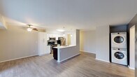 This well-appointed single-floor unit offers a thoughtfully designed open-concept layout that seamlessly connects the kitchen and living areas. The kitchen is a standout feature, equipped with stainless steel appliances including a refrigerator, microwave, and range, complemented by crisp white cabinetry, dark lower cabinetry with brushed nickel hardware, and light quartz countertops. A central island with a built-in sink adds both functionality and a natural gathering point. Pendant lighting and a ceiling fan enhance the space's modern aesthetic.

The living area extends from the kitchen, finished with rich hardwood-style flooring and anchored by a sliding glass door that opens to a private balcony, allowing natural light to pour in and offering pleasant outdoor views. A ceiling fan keeps the space comfortable year-round.

The bedrooms feature plush wall-to-wall carpeting and large windows fitted with vertical blinds, providing a quiet and comfortable retreat. The bathrooms are finished with dark vanity cabinets, marble-style countertops, and framed mirrors. One bathroom includes a walk-in shower with built-in shelving, while a second features a full vanity with ample storage. Light hardwood-style flooring ties the wet areas together cohesively throughout.