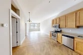 Located at 721 N Clinton St in Syracuse, NY, this two-bedroom, one-bathroom unit offers a well-designed single-floor layout with a functional and open feel. The kitchen and living room flow seamlessly together in an open-concept arrangement, anchored by a warm chandelier and natural light from a forward-facing window. The kitchen is equipped with a full suite of stainless steel appliances — including a range, microwave, dishwasher, and refrigerator — complemented by warm-toned wood cabinetry and granite-style countertops. Distinctive polished concrete flooring runs throughout the main living areas, adding an industrial character to the space. The primary bedroom is generously sized, featuring a ceiling fan, large windows that bring in ample natural light, and access to a dedicated closet with built-in shelving. The second bedroom offers a quieter, more compact layout with neutral tones and natural light. A full bathroom serves the unit, complete with a soaking tub, vanity with under-sink storage, and a lighted mirror. Three closets throughout the unit provide abundant storage. The neutral gray and white color palette, clean white trim, and thoughtful layout make this a practical and inviting space.