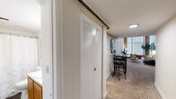 Located at 91 Elm St in Manchester, CT, this two-story, one-bedroom, one-bathroom unit blends industrial character with comfortable living across two well-proportioned floors. The main level hosts the primary living areas, including two living room spaces, a kitchen, and a bathroom, while the upper level accommodates the bedroom. Soaring ceilings and dramatic floor-to-ceiling arched windows framed by exposed brick walls define the living room, flooding the space with natural light and lending a striking loft-like aesthetic. Carpeted floors add warmth throughout the living areas. The kitchen features warm wood cabinetry, ample counter space on both sides, a stainless steel sink, and easy-care wood-look flooring, providing a functional and efficient layout. The bedroom is a serene retreat with its own soaring ceilings, an exposed brick arched window, a built-in closet, and soft carpeting. The bathroom is well-appointed with a tub/shower combination, wood-look flooring, and a vanity with sink. A staircase connects the two floors, as seen in the architectural overview, reinforcing the unit's distinctive two-level design. The combination of industrial elements and modern finishes gives this space a unique, characterful ambiance.