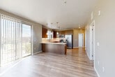 Located at 17607 East 61st Avenue in Denver, CO, this well-appointed 2-bedroom, 2-bathroom residence offers a thoughtfully designed single-level layout. The open-concept living, dining, and kitchen area serves as the heart of the home, featuring light wood-style flooring, pendant lighting, and a large kitchen island with a crisp white countertop. The kitchen is outfitted with rich walnut-toned cabinetry, a full suite of stainless steel appliances including a refrigerator with ice maker, electric range, microwave, and dishwasher, plus a bright window over the sink. Sliding glass doors lead to a private balcony, bringing in abundant natural light and outdoor views. A central hallway connects the two bedrooms, closets, bathrooms, and a laundry room. The primary bedroom is generously sized with carpeted flooring, a ceiling fan, and multiple windows. The second bedroom also features carpet and a wide window arrangement offering views of the surroundings. Both bathrooms are cleanly finished; one includes a glass-enclosed walk-in shower with white subway tile surround and chrome fixtures. Additional spaces include a pantry, utility room, and ample closet storage, rounding out a functional and comfortable home.