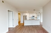 This contemporary 990 square foot apartment offers a harmonious blend of style and functionality. The open-concept living area is bathed in natural light, courtesy of floor-to-ceiling windows that provide stunning views of the surrounding landscape. The kitchen boasts sleek white cabinetry, stainless steel appliances, and a spacious granite-topped island, perfect for casual dining or entertaining.

The two bedrooms are generously sized, with the primary bedroom measuring 160 square feet. Both bathrooms feature modern fixtures, including vessel sinks and glass-enclosed showers. The master bathroom impresses with a double vanity and ample storage space.

Throughout the apartment, light-toned hardwood flooring creates a sense of warmth and continuity. The living spaces are thoughtfully designed with recessed lighting and smooth, white walls that serve as a blank canvas for personal decor.

A standout feature is the corner balcony, accessible through sliding glass doors, offering an extension of the living space and a perfect spot for outdoor relaxation. The apartment's layout is efficient, with hallways connecting the various rooms and a closet for additional storage.

This residence combines urban sophistication with comfortable living, making it an ideal home for those who appreciate modern design and city views.