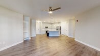 Located at 523 S Madison Ave in Greenwood, Indiana, this single-floor 2-bedroom, 2-bathroom residence offers a thoughtfully designed open-concept layout with modern finishes throughout. The heart of the home is a bright, open living and kitchen area anchored by a striking curved island with a white quartz countertop, undermount sink, and built-in shelving. The kitchen features white shaker cabinetry, a subway tile backsplash, stainless steel appliances including a French door refrigerator and range, and stylish pendant lighting overhead. A ceiling fan enhances the spacious living area, which is bathed in natural light from large windows and a glass-panel entry door. Wood-look flooring extends throughout the main living spaces, creating a cohesive and contemporary feel. The generously sized primary bedroom is carpeted for comfort, includes a ceiling fan, and offers ample closet space. The second bedroom is equally comfortable with soft carpet and neutral tones. Both bathrooms are well-appointed; one features a tub/shower combo with marble-look tile surround and wood-look flooring. Additional conveniences include a dedicated laundry room, pantry, and four closets, providing abundant storage throughout the residence.