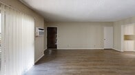 Located at 7050 Jordan Ave in the Canoga Park neighborhood of Los Angeles, this single-story, one-bedroom, one-bathroom unit offers a practical and well-organized layout across a comfortable footprint. The open-concept living and dining area serves as the heart of the home, featuring wood-style flooring, neutral-toned walls, and a textured ceiling throughout. A ceiling fan and wall-mounted air conditioning unit provide year-round climate control, while large vertical-blind-covered windows allow generous natural light to fill the space. The kitchen is equipped with warm honey-toned wood cabinetry, a tile backsplash, light countertops, and an electric cooktop, with ample upper and lower cabinet storage. A built-in wall shelf unit adds a functional display area in the main living space. The bedroom is a well-sized private retreat with its own closet and a window that brings in additional natural light. The bathroom features a combined tub and shower enclosure with sliding glass doors, a vanity with light-toned countertop and white cabinetry, and a high window for ventilation. A dedicated closet and hallway round out the layout, contributing to the unit's efficient use of space throughout.