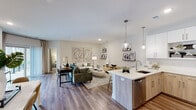 Located at 1001 Compass Way in Newark, Delaware, this single-floor residence offers a thoughtfully designed open-concept layout that seamlessly connects the kitchen, dining, and living areas. The kitchen is a standout feature, equipped with stainless steel appliances, a gas range, built-in microwave, and a large refrigerator. Crisp white upper cabinetry contrasts elegantly with warm wood-toned lower cabinets, all topped with quartz countertops. A peninsula with pendant lighting and bar seating provides both additional prep space and a casual dining option. The open living area is bathed in natural light from large windows and sliding glass doors that lead to an outdoor balcony. Wide-plank hardwood-style flooring flows throughout the main living spaces, lending warmth and continuity. A dedicated dining area offers ample room for a full table setting. Both bedrooms feature plush carpeting and generous natural light, with the second bedroom enjoying a bright window view. Two bathrooms are finished with large-format tile flooring and wood-accented vanities with quartz countertops — one featuring a soaking tub and shower combo, the other a glass-enclosed walk-in shower. The overall aesthetic is clean, modern, and cohesive throughout.
