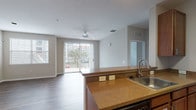 This single-floor residence offers a thoughtfully designed open-concept layout that seamlessly connects the kitchen, dining, and living areas. The living space is finished with warm-toned wood-look flooring and features a ceiling fan, recessed lighting, and a sliding glass door that opens to a private balcony, allowing natural light to flow throughout. Neutral-toned walls complement the overall aesthetic, creating a bright and inviting atmosphere.

The kitchen is well-equipped with warm wood cabinetry, granite-style countertops, a tile backsplash, and black appliances including a refrigerator, range, and microwave. A peninsula with a built-in sink and breakfast bar connects the kitchen to the living area. Adjacent to the kitchen is a dedicated laundry room with a full-size washer and dryer.

The primary bedroom is generously sized, featuring plush carpet flooring, a ceiling fan, and large bay windows that invite natural light. It includes a spacious walk-in closet outfitted with wire shelving. The bathroom is appointed with tile flooring, a vanity with storage, and a full soaking tub with shower. An additional bedroom, also carpeted with a ceiling fan and window, offers versatile use as a guest room or home office.