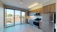 Located at 1280 SE Nehalem St in Portland, Oregon, this thoughtfully designed single-floor residence offers a clean, modern aesthetic throughout. The open kitchen is a standout feature, equipped with a full suite of stainless steel appliances including a gas range, built-in microwave, dishwasher, and refrigerator. Warm wood-tone cabinetry pairs with light countertops and a classic white tile backsplash, creating a functional and visually appealing space. Light vinyl plank flooring runs seamlessly through the main living and kitchen areas, contributing to the unit's bright, contemporary feel. Large sliding glass doors connect the main living area directly to a private outdoor balcony, flooding the interior with abundant natural light and offering open views of the surrounding Portland neighborhood. The bedroom features neutral gray walls, warm-toned flooring, recessed lighting, and direct access to a closet, providing a calm and practical retreat. The bathroom is well-appointed with a wood-finish vanity, quartz-style countertop, integrated sink, and a full tub and shower combination finished in clean white tile. Neutral tones and modern finishes are consistent throughout, giving the entire space a cohesive and contemporary character.