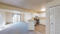 Located at 2276 E Cork St in Kalamazoo, Michigan, this single-floor unit offers a thoughtfully updated interior with a clean, modern aesthetic throughout. The open-concept kitchen is a standout feature, showcasing crisp white shaker cabinetry extending to the ceiling for ample storage, light stone-patterned countertops, a peninsula with additional workspace, and a full suite of stainless steel appliances including a gas range and refrigerator. Wood-look flooring anchors the kitchen, transitioning seamlessly into the adjoining living area. The spacious living room is finished with plush carpeting and features a sliding glass door that fills the space with natural light and provides access to an outdoor balcony with wooded views. The bedroom is a comfortable, well-proportioned space with carpet flooring and a window fitted with blinds, allowing for natural light and privacy. The bathroom is outfitted with matching white cabinetry, stone-patterned countertops, a large vanity mirror, and wood-look tile flooring, maintaining a consistent, updated style. Louvered closet doors and dedicated entry storage add practical functionality. The unit presents a bright, move-in ready interior with cohesive finishes throughout.