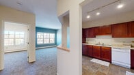 Located at 2323 26th Ave N in Minneapolis, MN, this one-bedroom, one-bathroom unit offers a practical and comfortable single-floor layout. The kitchen is a standout feature, showcasing rich dark-cherry cabinetry that extends to the ceiling, ample counter space with a double sink, and warm tile flooring that adds a grounded, earthy tone. White appliances including a refrigerator, range, and dishwasher complete the functional cooking space. The bedroom is a well-proportioned room featuring soft wall-to-wall carpeting, a large multi-pane window that invites abundant natural light and views of the surrounding neighborhood, and a wall-mounted climate control unit alongside baseboard heating. A dedicated closet provides convenient storage. The living area continues the carpeted flooring and features a bold blue accent wall paired with a large window, creating a bright and visually interesting space. The bathroom maintains consistency with the tile flooring seen in the kitchen and includes a vanity with matching cabinetry, a toilet, and a shower with a curtain rod. The unit's neutral color palette throughout provides a clean, move-in-ready canvas suitable for a variety of interior styles.