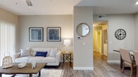 This single-floor residence offers a thoughtfully designed layout with a bright, open-concept living area anchored by wood-look flooring, neutral warm-gray walls, and a ceiling fan overhead. Large sliding glass doors flood the space with natural light and provide access to an outdoor area. The living room flows seamlessly into the surrounding spaces, creating a comfortable and connected environment.

The kitchen is a functional highlight, featuring white cabinetry, granite-style countertops, a peninsula breakfast bar, and a full suite of white appliances including a refrigerator, electric range, built-in microwave, and a double-basin sink. The layout maximizes storage and counter space efficiently.

Two bedrooms offer plush carpeting, neutral walls, and ample room for rest and relaxation. One bedroom includes a ceiling fan and a window with natural light, while both rooms provide a calm, restful atmosphere. A dedicated bathroom features wood-look flooring, a tub-shower combination, and classic finishes.

A convenient in-unit laundry area is equipped with a full-size washer and dryer, complemented by overhead shelving for added storage. Throughout the residence, consistent use of neutral tones, wood-look flooring, and clean finishes creates a cohesive and inviting aesthetic.