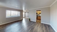 This single-floor, 2-bedroom, 2-bathroom residence offers a thoughtfully designed layout with a blend of modern finishes and functional living spaces. The open living area is anchored by rich, dark hardwood-style flooring that flows throughout the main areas, complemented by neutral gray walls, crown molding, and a ceiling fan. Large windows with vertical blinds allow natural light to fill the space, enhancing its airy feel. A hallway connects the living area to the rest of the home, leading to a dedicated kitchen adorned with warm honey-toned wood cabinetry, dark countertops, and a full suite of stainless steel appliances including a refrigerator, dishwasher, and range. The kitchen also features wood-look flooring that ties seamlessly into the main living space. Both bedrooms are carpeted for comfort, with crown molding, bright windows fitted with horizontal blinds, and ample natural light. One bedroom features a bold accent wall in deep slate blue, adding a distinctive design touch. The bathrooms are well-appointed, with one featuring a tub-shower combination clad in elegant marble-look surrounds. Closet storage is conveniently accessible, with at least one bedroom offering a dedicated closet space adjacent to a bathroom.