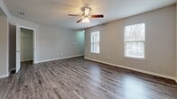Located at 101 Little Bay Ave in Yorktown, Virginia, this single-floor residence offers a functional and well-appointed layout designed for comfortable everyday living. The main living area features durable hardwood-style flooring, neutral gray walls, a textured ceiling, and a ceiling fan with integrated lighting. Multiple windows dressed with horizontal blinds allow ample natural light to fill the space. An adjacent area mirrors this open feel, also outfitted with a ceiling fan and similarly styled flooring, providing flexible use as a dining or secondary living space.

The kitchen is equipped with warm-toned wood cabinetry, granite countertops, a stainless steel sink, and black appliances including a gas range, dishwasher, and range hood, all set above wood-look vinyl flooring.

The bedrooms are carpeted in a soft, neutral tone and include closets with built-in rods for storage. One bedroom features a private exterior door alongside a window, adding both convenience and light. The bathroom is fitted with granite countertops at the vanity, a large mirror, and a full soaking tub-shower combination with chrome fixtures. The overall aesthetic throughout is clean, neutral, and move-in ready.