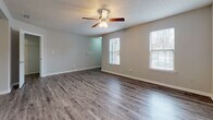 Located at 101 Little Bay Ave in Yorktown, Virginia, this single-floor residence offers a functional and well-appointed layout designed for comfortable everyday living. The main living area features durable hardwood-style flooring, neutral gray walls, a textured ceiling, and a ceiling fan with integrated lighting. Multiple windows dressed with horizontal blinds allow ample natural light to fill the space. An adjacent area mirrors this open feel, also outfitted with a ceiling fan and similarly styled flooring, providing flexible use as a dining or secondary living space.

The kitchen is equipped with warm-toned wood cabinetry, granite countertops, a stainless steel sink, and black appliances including a gas range, dishwasher, and range hood, all set above wood-look vinyl flooring.

The bedrooms are carpeted in a soft, neutral tone and include closets with built-in rods for storage. One bedroom features a private exterior door alongside a window, adding both convenience and light. The bathroom is fitted with granite countertops at the vanity, a large mirror, and a full soaking tub-shower combination with chrome fixtures. The overall aesthetic throughout is clean, neutral, and move-in ready.