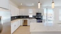 This thoughtfully designed 2-bedroom, 2-bathroom residence at 4700 E Kentucky Ave offers a modern and functional single-floor layout. The open-concept kitchen is a standout feature, showcasing crisp white shaker cabinetry, light quartz countertops, a bold geometric tile backsplash, and a full suite of stainless steel appliances including a French door refrigerator with ice maker, electric range, microwave, and dishwasher. A pendant light and recessed lighting illuminate the space, which flows seamlessly into the living area via light wood-style flooring.

Both bathrooms are finished with white vanities, quartz countertops, and the same geometric tile accent seen in the kitchen. One bathroom features a glass-enclosed walk-in shower, while the second offers a full soaking tub with tiled surround. Large mirrors and chrome fixtures complete each bathroom's clean, contemporary aesthetic.

The bedrooms are carpeted and receive natural light through window blinds. A dedicated in-unit laundry closet houses a full-size Electrolux washer and dryer set with overhead wire shelving for storage. Recessed lighting and clean white walls throughout the unit contribute to a bright, modern ambiance, making this a well-equipped and move-in-ready residence.