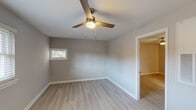 Located at 718 Hampstead Pl in Raleigh, NC, this single-floor home has been thoughtfully updated with a clean, modern aesthetic carried consistently throughout. Light wood-look luxury vinyl flooring runs across the entire home, complemented by fresh neutral gray walls and crisp white trim, creating a bright and cohesive atmosphere.

The living area welcomes you through a front entry door framed by large, light-filtering blinds that allow natural light to pour in. A ceiling fan overhead adds both style and comfort to the space.

The kitchen stands out as a highlight of the home, featuring white shaker-style cabinetry, granite-look countertops, a classic subway tile backsplash, and a full suite of stainless steel appliances including a refrigerator, range, and over-the-range microwave. A window above the sink brings in additional natural light, and a side entry door provides convenient access.

The bedrooms are well-proportioned, each outfitted with ceiling fans and windows dressed with blinds, providing a comfortable and versatile layout. The neutral tones and consistent flooring give each room a sense of openness.

The bathroom is neatly appointed with a shaker-style vanity, brushed nickel fixtures, a framed mirror, and a tub-shower combination, maintaining the home's clean and updated character throughout.