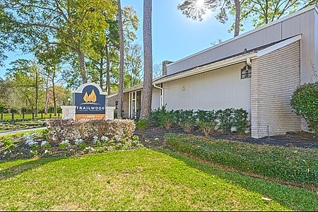 Trailwood Village Apartments Exterior View with Apartments Lawn View and Company Logo Signage - Trailwood Village Apartments