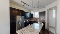 This thoughtfully designed two-story home offers a blend of modern finishes and functional living spaces across both levels. The standout kitchen is appointed with rich, dark espresso cabinetry, sleek granite countertops, and a full suite of stainless steel appliances including a French door refrigerator, built-in microwave, gas range, and dishwasher. A large kitchen island provides additional prep space and casual seating, while stylish pendant and track lighting illuminate the room. A gray subway tile backsplash adds a contemporary touch throughout the kitchen.

The living areas feature rich dark hardwood flooring and are bathed in natural light from large French doors that open to the outdoors. Ceiling fans in the main living spaces enhance comfort and airflow. Carpeted bedrooms offer a softer, quieter retreat, also benefiting from French door access and ample natural light streaming through slatted blinds.

The bathrooms are finished with clean, modern details. A full bathroom features dark cabinetry, a double vanity with white countertops, large-format tile flooring, and a walk-in closet with built-in shelving. A secondary powder room includes a pedestal sink and an oval mirror, maintaining the home's clean aesthetic throughout.
