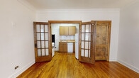 Located at 2350 N Cambridge Ave in Chicago's desirable Lincoln Park neighborhood, this single-floor unit blends vintage architectural charm with functional living spaces. Hardwood floors extend throughout, gleaming with warmth and adding a cohesive, classic aesthetic to every room.

The living area is generously proportioned, featuring crown molding, a ceiling fan with light fixture, and multiple windows framed in rich wood trim that allow natural light to fill the space. A cast-iron radiator adds to the unit's historic character. The entry door is a solid, heavy wood panel that reinforces the building's vintage appeal.

A standout architectural feature is the set of swinging French doors with multi-pane glass panels that separate the living area from the kitchen, offering both visual openness and the option for privacy. The kitchen is equipped with oak cabinetry, white subway tile backsplash, a gas range, dishwasher, and refrigerator. A cast-iron radiator and a solid wood back door are also present within the kitchen.

The bedroom receives abundant natural light through a large wood-trimmed window with views of surrounding greenery, and includes a ceiling fan overhead. The bathroom continues the vintage theme with classic penny-tile flooring, a full soaking tub with white tile surround, and a window for natural ventilation.