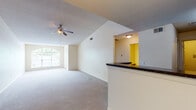 This single-floor residence offers a well-designed open-concept layout that seamlessly connects the main living areas. The spacious living room immediately draws attention with its vaulted ceilings and a ceiling fan, creating a sense of openness and airflow. Plush wall-to-wall carpeting runs throughout the living and bedroom areas, adding warmth underfoot, while hardwood-style flooring defines the entryway and kitchen zones. Natural light filters generously through an arched window at the front entry and additional windows throughout, brightening every corner of the home.

The kitchen is efficiently arranged and features dark granite-style countertops, light wood cabinetry, and black appliances including a range with an over-the-range microwave and a refrigerator. A breakfast bar peninsula connects the kitchen to the living and dining areas, providing both a functional workspace and a casual gathering spot. A pendant light fixture overhead adds a finishing touch to the dining area.

The bedroom is a comfortable, carpeted retreat with its own ceiling fan and a window dressed with horizontal blinds, offering privacy while still welcoming natural light. The bathroom includes a full tub-shower combination with clean white tile surround and hardwood-style flooring. Overall, the residence provides a functional, comfortable layout with practical finishes throughout.