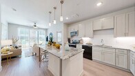 This thoughtfully designed two-bedroom, two-bathroom residence offers a cohesive single-floor layout that maximizes both comfort and functionality. Light wood-look flooring flows throughout, creating a warm, unified aesthetic across all rooms.

The kitchen is a standout feature, showcasing white shaker cabinetry, a subway tile backsplash, stainless steel appliances, and a generously sized granite island with bar seating and pendant lighting overhead — ideal for both casual dining and entertaining.

The living room is bright and welcoming, featuring a ceiling fan and floor-to-ceiling sliding glass doors that invite natural light and provide outdoor access. The open, airy feel makes the space feel expansive and connected to the exterior.

The primary bedroom is a comfortable retreat with large windows allowing ample natural light, complemented by a ceiling fan. The second bedroom also features natural light and a clean, neutral finish. Both bathrooms are well-appointed with granite countertops, shaker-style cabinetry, and wood-look flooring. One bathroom includes a soaking tub and walk-in shower, while the other features a frameless glass shower.

Two closets provide organized storage, including a walk-in closet with built-in shelving. A hallway connects the spaces seamlessly, completing this well-planned, modern residence.