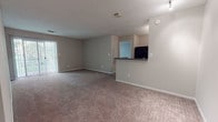 Located at 1187 Ridgewood Rd in Middletown, Connecticut, this single-floor unit offers a practical and comfortable layout designed for everyday living. The open living area is generously sized, finished with neutral-toned carpet and soft beige walls, and features a sliding glass door that invites natural light. A half-wall partition separates the living space from the kitchen, which is outfitted with warm cherry wood cabinetry, dark granite-style countertops, wood-look tile flooring, and a full suite of black appliances including a gas range, refrigerator, and dishwasher. The bedrooms are carpeted and bathed in natural light from large windows with outdoor views of surrounding greenery. Each bedroom benefits from dedicated closet space, including roomy reach-in closets with bifold doors, and a hallway offers additional storage. The two full bathrooms are thoughtfully appointed with cherry wood vanities, dark countertops, large mirrors, tub-shower combinations with tile surrounds, and wood-look vinyl flooring. Textured ceilings are consistent throughout the unit, and neutral wall tones create a clean, cohesive aesthetic that is easy to personalize.