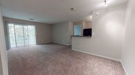 Located at 1187 Ridgewood Rd in Middletown, Connecticut, this single-floor unit offers a practical and comfortable layout designed for everyday living. The open living area is generously sized, finished with neutral-toned carpet and soft beige walls, and features a sliding glass door that invites natural light. A half-wall partition separates the living space from the kitchen, which is outfitted with warm cherry wood cabinetry, dark granite-style countertops, wood-look tile flooring, and a full suite of black appliances including a gas range, refrigerator, and dishwasher. The bedrooms are carpeted and bathed in natural light from large windows with outdoor views of surrounding greenery. Each bedroom benefits from dedicated closet space, including roomy reach-in closets with bifold doors, and a hallway offers additional storage. The two full bathrooms are thoughtfully appointed with cherry wood vanities, dark countertops, large mirrors, tub-shower combinations with tile surrounds, and wood-look vinyl flooring. Textured ceilings are consistent throughout the unit, and neutral wall tones create a clean, cohesive aesthetic that is easy to personalize.
