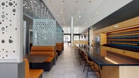 This thoughtfully designed single-floor amenity space combines social, recreational, and functional zones within a cohesive modern aesthetic. The open-plan layout is anchored by soaring double-height ceilings and large pendant light installations—slender gold and white fixtures cascading from above—that create a dramatic yet welcoming ambiance throughout.

The central lounge and social hub features a long dark-topped kitchen island with bar seating, warm natural wood cabinetry, stainless steel appliances, a built-in oven, and a vibrant multicolored tile backsplash. Adjacent booth seating, upholstered in rich cognac leather and separated by decorative perforated metal screens with organic cutout patterns, provides semi-private gathering areas.

An expansive lounge zone offers comfortable sectional seating, a large wall-mounted display, and built-in shelving, while a pool table and high-top bar seating add recreational variety. Natural light fills the space through large windows and glass doors that open to an outdoor terrace area.

A dedicated corridor leads to private meeting and conference rooms, one featuring artistic wallcovering and a pendant-lit dining table. Near the entrance, a reception-style desk, hexagonal tile wall accent, and warm wood millwork create a polished arrival experience. Large-format tile flooring ties the entire space together cohesively.