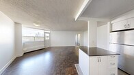 Located on the 7th floor at 3122 Hurontario Street in Mississauga, this two-bedroom, one-bathroom unit offers a well-organized layout across a single floor. The combined kitchen and living area serves as the heart of the home, featuring a modern kitchen with white cabinetry, dark countertops, a central island, stainless steel appliances including a refrigerator and dishwasher, and a subtle tile backsplash. The kitchen transitions seamlessly into the living area, where rich parquet wood flooring extends throughout the space. A hallway connects the bedrooms and bathroom, providing a clear and practical flow. The primary bedroom is a comfortable size and benefits from a large window that frames views of the Mississauga cityscape, including neighboring high-rises and greenery. The second bedroom also features parquet flooring and a mirrored sliding closet, adding depth and storage. The bathroom is finished with classic white subway tiles surrounding a full soaker tub and shower combination, complemented by a small window for natural light. Textured ceilings are consistent throughout the unit, and clean white walls create a bright, neutral canvas. Baseboard heating is present in the main living areas and bedrooms.