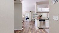 This well-appointed two-bedroom, two-bathroom residence in Rocklin, California offers a functional and stylish single-level layout. Wood-look flooring flows throughout the main living areas, complemented by neutral warm tones that create a cohesive and inviting atmosphere.

The kitchen is equipped with stainless steel appliances — including a range, microwave, dishwasher, and refrigerator — alongside white shaker cabinetry, granite countertops, and a tile backsplash. It opens conveniently to the dining area, which features crown molding and a ceiling fan, making it ideal for everyday meals and entertaining.

The living room is bright and welcoming, with sliding glass doors that invite natural light and provide direct access to an outdoor balcony with views of lush greenery. The primary bedroom offers comfortable proportions with plush carpeting and a closet with sliding panel doors. The second bedroom mirrors this cozy aesthetic. Both bathrooms feature granite-topped white vanities and wood-look flooring.

Additional highlights include a dedicated in-unit laundry room with washer and dryer hookups and wire shelving for storage. The entrance and hallway connect all areas seamlessly, completing this practical and attractive floor plan.
