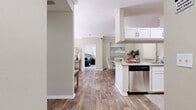 This well-appointed two-bedroom, two-bathroom residence in Rocklin, California offers a functional and stylish single-level layout. Wood-look flooring flows throughout the main living areas, complemented by neutral warm tones that create a cohesive and inviting atmosphere.

The kitchen is equipped with stainless steel appliances — including a range, microwave, dishwasher, and refrigerator — alongside white shaker cabinetry, granite countertops, and a tile backsplash. It opens conveniently to the dining area, which features crown molding and a ceiling fan, making it ideal for everyday meals and entertaining.

The living room is bright and welcoming, with sliding glass doors that invite natural light and provide direct access to an outdoor balcony with views of lush greenery. The primary bedroom offers comfortable proportions with plush carpeting and a closet with sliding panel doors. The second bedroom mirrors this cozy aesthetic. Both bathrooms feature granite-topped white vanities and wood-look flooring.

Additional highlights include a dedicated in-unit laundry room with washer and dryer hookups and wire shelving for storage. The entrance and hallway connect all areas seamlessly, completing this practical and attractive floor plan.