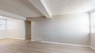 This single-floor unit offers a clean, neutral aesthetic throughout, designed for comfortable everyday living. The open living and dining areas are finished with light-toned hardwood-style flooring, complemented by soft gray and beige walls and textured ceilings. Structural beams add architectural definition to the main living space, which also features floor-level HVAC vents and multiple electrical outlets for practical use.

The kitchen is well-equipped with white shaker-style cabinetry, granite-look countertops, and a full suite of appliances including a stainless steel refrigerator, dishwasher, and a black electric range with overhead ventilation. Light hardwood-style flooring continues throughout the kitchen, creating a cohesive flow.

The bedrooms are carpeted for comfort and each room is fitted with a ceiling fan with integrated lighting. Multiple windows dressed with horizontal blinds allow generous natural light to filter in, providing views of the surrounding exterior. The rooms offer ample wall space, making them highly versatile for various furniture arrangements.

Overall, the unit presents a practical and well-maintained interior with consistent finishes, neutral tones, and thoughtful details that create a bright and livable environment throughout.