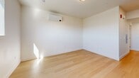 This 330 square foot studio apartment in Redwood City, CA, offers a well-designed living space on a single floor. The interior showcases a modern aesthetic with clean lines and a neutral color palette. Light wood flooring runs throughout, creating a warm and cohesive look. The apartment features a full kitchen equipped with sleek wooden cabinetry, stainless steel appliances, and a white countertop, optimizing the compact space. The bathroom boasts a spacious white tub-shower combination with built-in shelving and a curved shower rod. A wooden cabinet adds a touch of warmth to the predominantly white bathroom. The main living area is bright and airy, with a large window providing natural light and mountain views. The space is climate-controlled with a wall-mounted air conditioning unit. Recessed lighting throughout ensures even illumination. Despite its compact size, the apartment's thoughtful layout and design elements create a functional and inviting living environment.