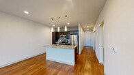 Located at 704 Williamson Street in Madison, WI, this well-appointed one-bedroom, one-bathroom unit offers a thoughtfully designed open-concept layout across a single floor. The combined kitchen and living area serves as the heart of the home, showcasing warm hardwood flooring, recessed lighting, and large windows that invite generous natural light and outdoor views. The kitchen is a standout feature, equipped with dark espresso cabinetry, stainless steel appliances including a refrigerator, range, and microwave, and a granite-topped island with an integrated sink and pendant lighting overhead — ideal for both everyday cooking and casual dining. A glass-paneled exterior door in the living area adds additional light and access. The hallway, also finished in hardwood, connects the main living space to the private quarters. The bedroom offers plush carpeting, a ceiling fan, and dual windows that frame outdoor views, creating a bright and comfortable retreat. An adjacent closet provides dedicated storage. The bathroom is finished with dark cabinetry, a white countertop vanity, a large mirror, tile flooring, and a full soaking tub with shower. Clean lines and a neutral color palette throughout lend the space a modern, cohesive aesthetic.