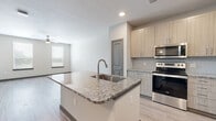 Located at 9445 FM-1464 N in Houston, TX, this well-appointed one-bedroom, one-bathroom unit offers a thoughtfully designed layout with modern finishes throughout. The open-concept kitchen and living area serves as the heart of the space, anchored by a large center island with a granite countertop and undermount sink. The kitchen is equipped with stainless steel appliances, including a range, over-the-range microwave, and a French door refrigerator, complemented by light wood-tone cabinetry and a subtle tile backsplash. Light wood-look flooring flows throughout the main living areas, lending warmth and continuity to the space. The living room benefits from multiple windows fitted with blinds, allowing for natural light and outdoor views, and includes a ceiling fan for added comfort. The bedroom features plush carpeting, a large window with outdoor views, and a dedicated closet. The bathroom is finished with a granite-topped vanity, wood-tone cabinetry with brushed nickel hardware, and wood-look flooring consistent with the rest of the unit. Hallways connecting the rooms are well-proportioned, contributing to the efficient and functional flow of the overall floor plan.