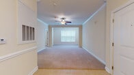Located at 114 Avalon Park Rd in Mooresville, North Carolina, this single-floor home offers a well-appointed layout designed for comfortable living. The main living area is generously sized, showcasing elegant crown molding, plush neutral carpeting, and a ceiling fan that adds both style and function. Large windows allow natural light to fill the space, creating a warm and inviting ambiance throughout.

The kitchen is outfitted with rich, warm-toned wood cabinetry, granite countertops, and black appliances including an electric range, built-in microwave, and dishwasher. Light tile flooring grounds the space and transitions seamlessly into the adjoining areas.

The bedrooms are carpeted and well-proportioned, each featuring natural light from windows with blinds. One bedroom is highlighted by a pendant light fixture and provides direct access to an adjoining room, offering flexible use of space. The living areas feature decorative column accents and ceiling fans with crown molding details.

The bathroom is finished with matching granite countertops, rich wood cabinetry, a tub-shower combination, and brushed nickel fixtures, including grab bars for added accessibility. Light tile flooring and a wall-mounted mirror complete the clean, cohesive design. Overall, this home presents a consistent, neutral palette with quality finishes throughout.