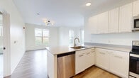 Located at 87 Union St in New Haven, CT, this well-appointed residence offers three bedrooms and three full bathrooms across a thoughtfully designed single-floor layout. The open-concept kitchen and living area serves as the heart of the home, showcasing crisp white shaker cabinetry, stainless steel appliances including a range, microwave, and refrigerator, and a peninsula with a built-in sink and neutral quartz-style countertops — ideal for both cooking and casual dining. Light wood-tone flooring runs throughout, creating a cohesive and airy aesthetic. Each bedroom is bright and generously proportioned, with large windows that frame views of the surrounding New Haven cityscape and greenery; one bedroom features sliding glass doors opening to a private balcony. The three bathrooms are finished to a consistent modern standard, featuring large-format tile flooring, walk-in showers with subway-style tile surrounds, matte black fixtures and hardware, and white vanities with gray countertops. Two hallways provide efficient circulation throughout the unit, and a dedicated closet offers additional storage. The overall ambiance is clean, contemporary, and light-filled, with a neutral color palette that lends itself to a variety of interior styles.