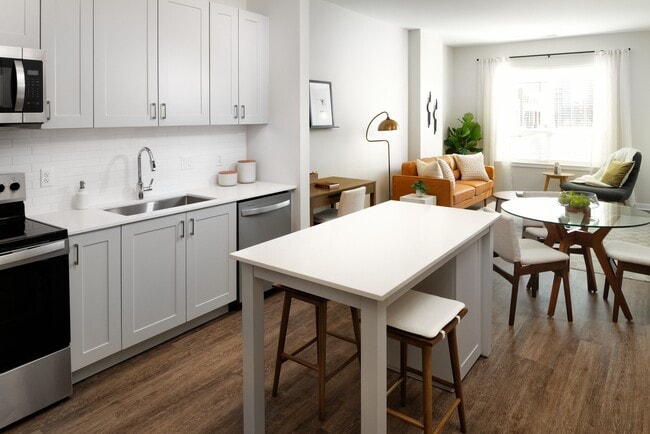 New West Phase - Finish Package III Kitchen with stainless steel appliances, white quartz countertops, grey cabinetry, and hard surface flooring throughout - Avalon Hunt Valley and Hunt Valley West